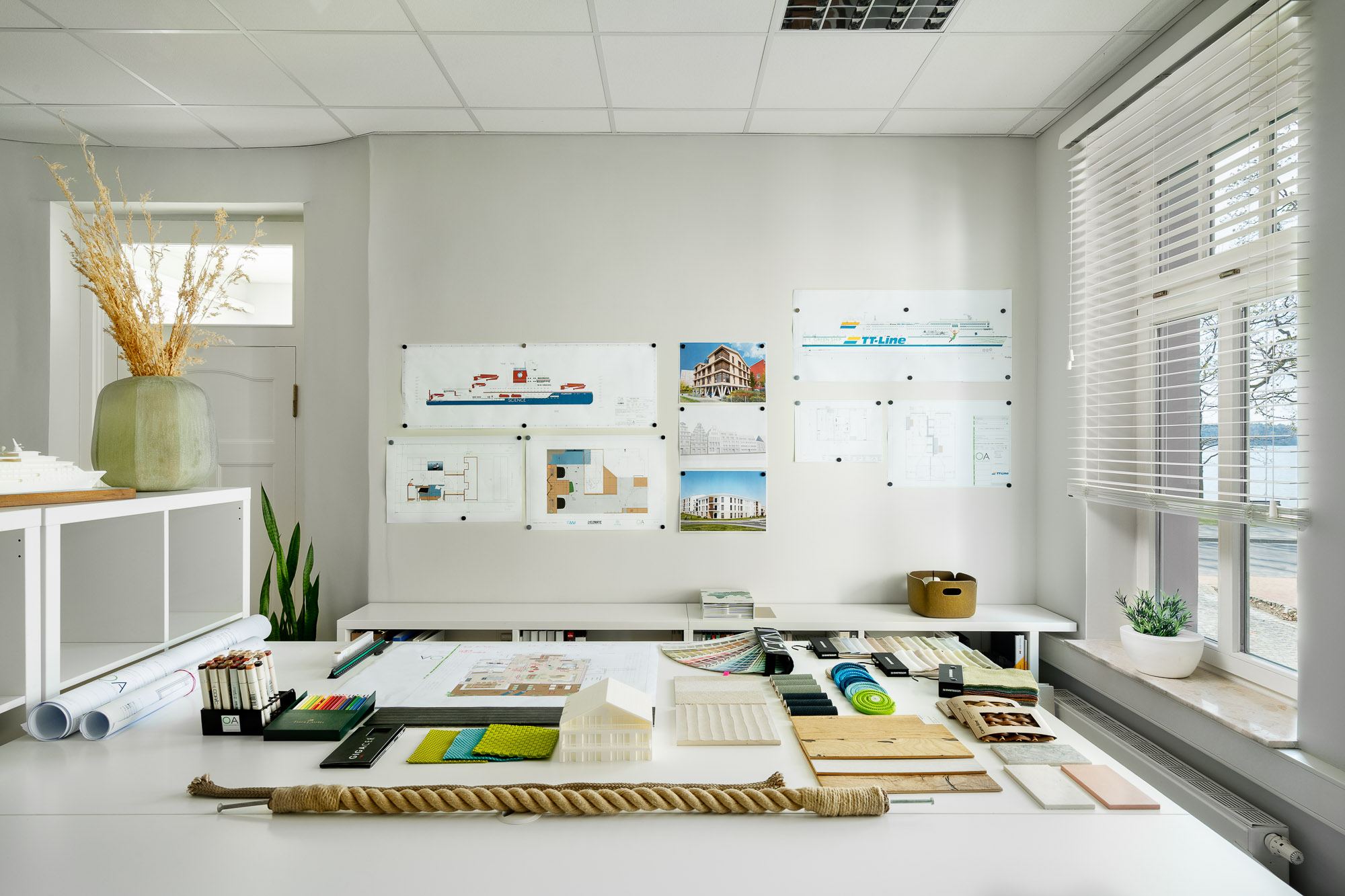 Planungstisch mit Zeichnungen, Materialmustern, Farbfächern und einem Architekturmodell